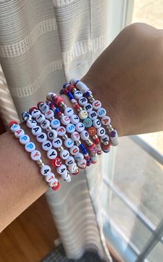 a woman's arm with several bracelets made to look like letters and numbers