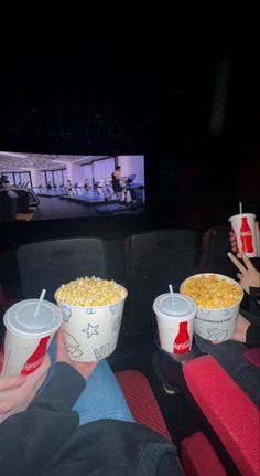 two buckets of popcorn sitting in front of a screen