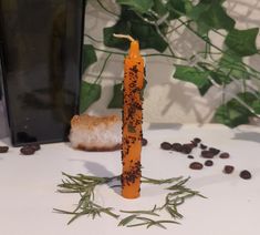 an orange candle sitting on top of a table next to coffee beans and a plant