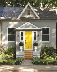 a yellow door sits in front of a gray house