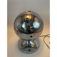 a chrome ball lamp with a person reflected in the mirror on it's side