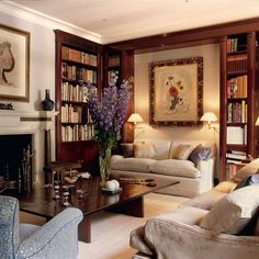 a living room filled with furniture and bookshelves next to a fire place in front of a fireplace