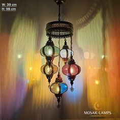 a chandelier hanging from the ceiling in front of a curtained window with lights on it