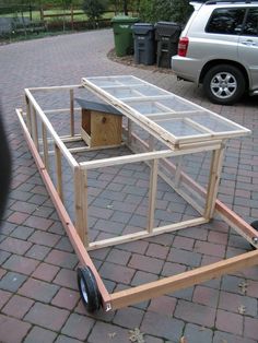 a wooden cart with a chicken house on it's back end and wheels attached to the cart