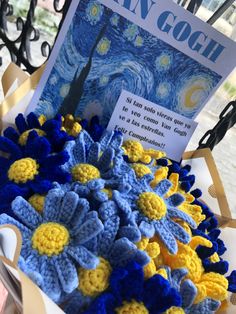 crocheted flowers are on display in a basket with an open book about van gogh