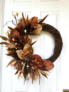 a wreath with dried leaves and flowers hanging on the front door to give it an autumn feel