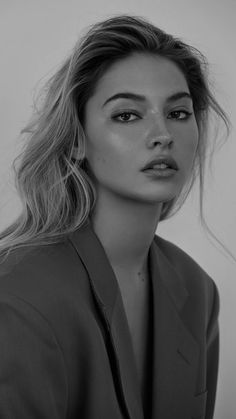 a black and white photo of a woman with long hair wearing a blazer jacket