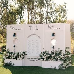 a couple of large white signs sitting on top of a lush green field next to trees