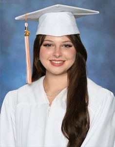 a young woman wearing a white graduation gown and a gold tassel on her head