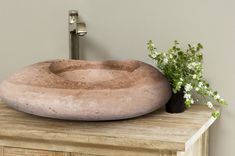 a large stone sink sitting on top of a wooden counter next to a vase with flowers