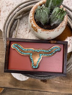 a wooden box with a cow skull on it and a cactus in the corner next to it