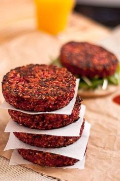 three hamburger patties stacked on top of each other next to a glass of orange juice