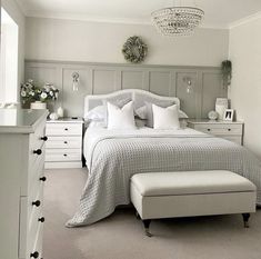 a bedroom with a bed, dressers and white furniture