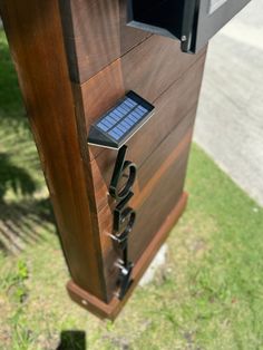 a solar powered mailbox on the side of a road with grass and trees in the background