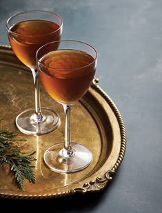 two glasses of wine sitting on top of a metal tray