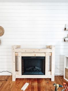 a living room with white walls and wood flooring, including a fireplace in the center