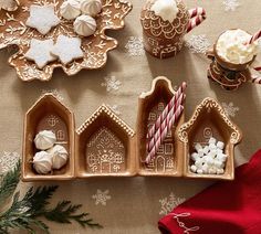 gingerbread houses, candy canes and cookies on a table with christmas decorations in the background