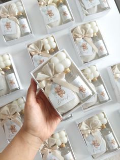 a hand holding a box with white chocolates in it and other candies on the table