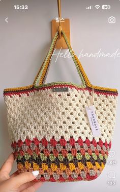 a hand holding a crocheted purse on a wooden hanger