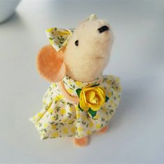 a small stuffed animal wearing a yellow flower dress