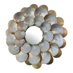 a circular mirror made out of seashells on a white background