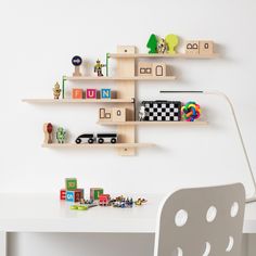 two wooden shelves on the wall above a desk with toy cars and toys in front of them