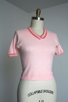 Fantastic hard-to-find knit top from the 1950s. I love finding the more casual daywear like this. This piece is in a wonderful shade of pink! Slight dolman sleeves, cute collar, and fitted waist.  Label: label has worn writing away so can't read it anymore.  Measurements: { medium + } Bust: 34"-40"  Waist: 30"-34"  Length: 19" Sleeve Length: 13" Condition: good vintage condition with a couple things to note: mostly just some repairs on collar and shoulder as shown. minor signs of wear - sold as Pink Knit Short Sleeve Tops, Pink Knit Tops With Short Sleeves, Pink Short Sleeve Knit Tops, Pink Knit Top With Short Sleeves, Retro Pink V-neck Top, Pink Retro V-neck Tops, Pink Short Sleeve Cotton Knit Top, Pink Short Sleeve Cotton Sweater, Pink Cotton Short-sleeved Sweater