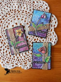 three small cards are sitting on a doily