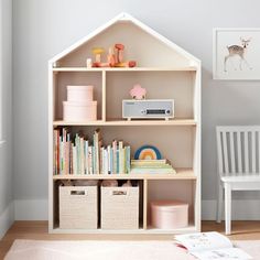 a white doll house shelf with books and toys on it in a child's room