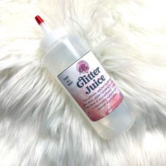 a bottle of silver juice sitting on top of a white furry surface