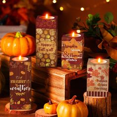 pumpkins and candles are on display in front of some fall themed boxes with autumn leaves