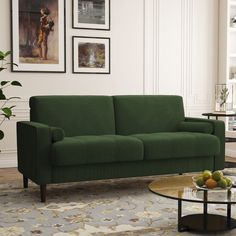 a living room with a green couch and coffee table in front of pictures on the wall