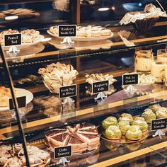 a display case filled with lots of different types of cakes and pies in glass cases