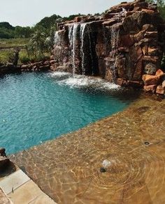 an outdoor pool with waterfall in the middle