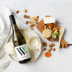 a bottle of wine sitting on top of a plate next to nuts and crackers