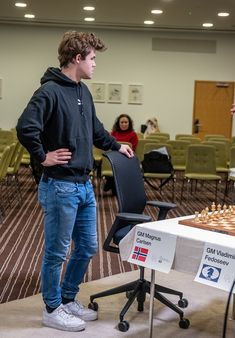 a man standing next to a table with chess on it