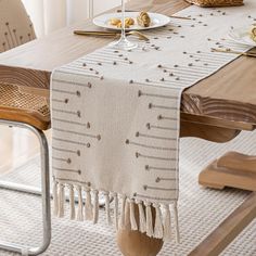 the table is set with plates and silverware on it, along with a beige runner