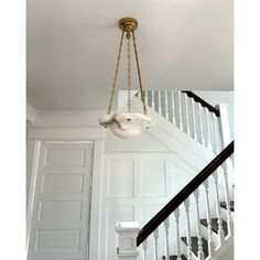 a chandelier hanging from the ceiling in a room with white walls and stairs