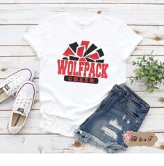 a t - shirt with the words wolfpack cheer on it next to ripped shorts