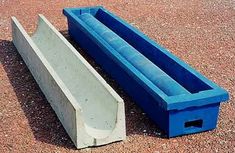 two cement troughs sitting on the ground next to each other, one blue and one gray