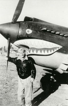 a man standing next to an airplane with a shark mouth on it