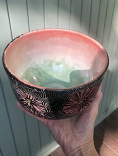 a hand holding a bowl with green liquid in it