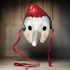 an elephant mask with a red hat on it's head is suspended upside down