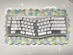 a computer keyboard and mouse on a colorful knitted place mat, with white keys