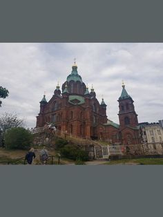 two people are walking up the steps to an old building with green roof and gold domes