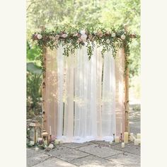 an outdoor ceremony with sheer curtains and flowers