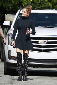 a woman in black dress and knee high boots