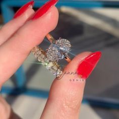 a woman's hand with red nails holding a diamond and gold ring on her finger