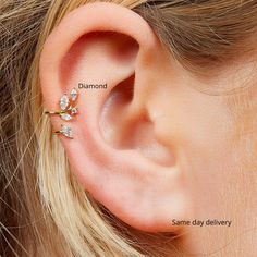 a close up of a person wearing an ear cuff with three small flowers on it