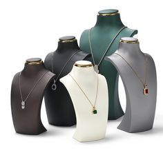 several necklaces and pendants are displayed on mannequins with different colors